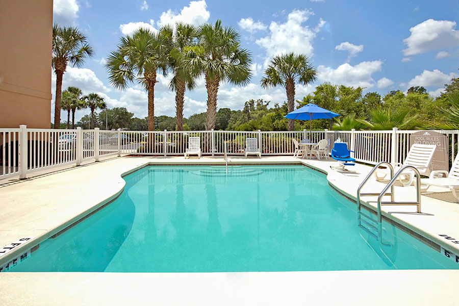 outdoor pool with patio chairs and pool lift