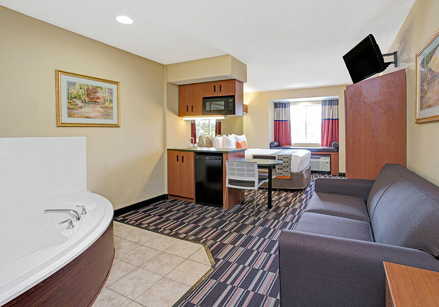guest suite with one queen bed, sofa, and jetted tub
